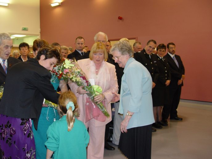 Amy-Leigh Daniel of Ogmore Vale Primary School, presents a bouquet to Edwina Hart AM, MBE. Joanna Daniel and Peggy Hughes look on.