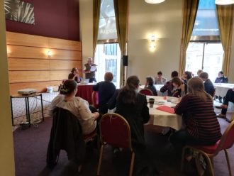 The conference included several breakout sessions, including this one about migration stories in the LGBT+ community, with Ourstory Scotland. A number of people are sat round a table | Community Archives and Heritage Group