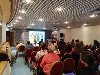 A breakout session at the CAHG 2019 Conference. Rows of people are sat on chairs looking towards a Powerpoint screen. | Community Archives and Heritage Group