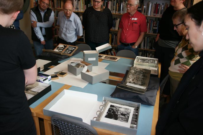 A group of people standing around some documents, listening to somebody telling them about the items | Image courtesy of Community Archives & Heritage Group Scotland