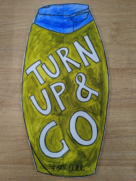 A hand painted cardboard cutout resembling a shampoo bottle. Over the bottle it says 